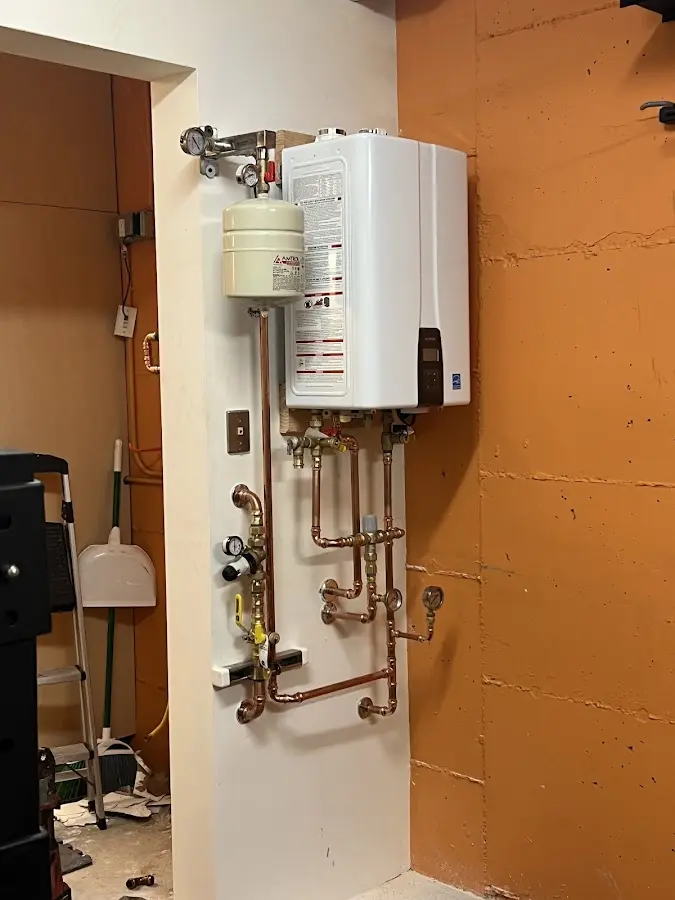 Plumbing technician inspecting water heater connections in Arundel